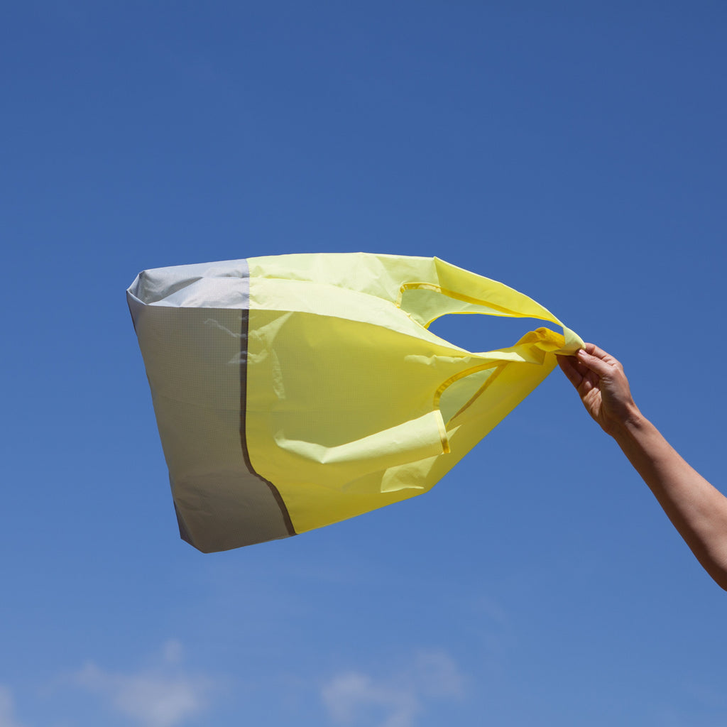 Yellow and grey recycled foldable shopping bag flying in air